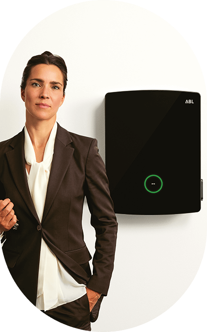Frau steht neben an Wand montierter ABL eM4 Wallbox | ABL eMobility
