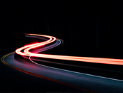 Langzeitbelichtung Autoscheinwerfer auf Straße im dunkeln – Elektrofahrzeuge fahren mit Ladelösungen von ABL eMobility